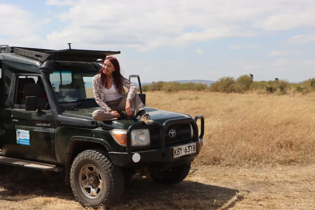 Luxury Kenya safari - tourist on a game drive poses for a picture seated on our safari Lancruiser’s van